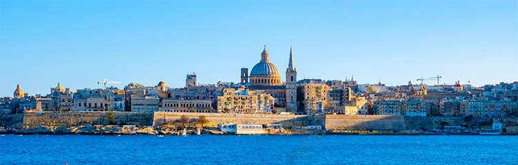 Greg Berryman and SY Alegria sailing into Valletta Malta with panoramic view over Valletta old town at sunset